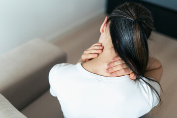 Naklejka premium Woman with chronic illness feels discomfort in living room while touching her neck