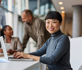 Portrait of a group of young business people having a meeting in the office. Teamwork and success concept, portrait of a smart young businesswoman using a laptop
