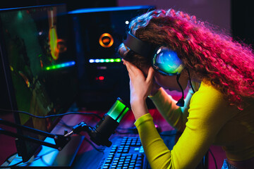 Sad female gamer frustrated while gaming online with neon lights and digital technology © deagreez