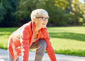 Smiling active senior woman standing in start position,  jogging running and walking doing fitness...
