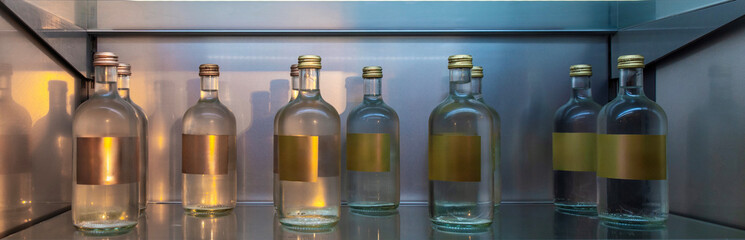 Glass bottles with metallic caps and golden labels on the shelf