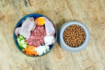 Natural raw dog food and kibble dog food in bowls on wooden background Top view