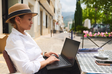 Woman Working on a Laptop at an Outdoor Caf? Table on a Sunny Day