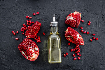 Glass bottle of pomegranate seed oil in a glass bottle and fresh fruit on a table, top view