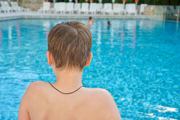 Teenage boy by the pool watching girls swim, concept of growing up, interest