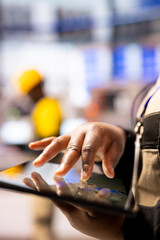 African american specialist in smart factory working on a tablet to design manufacturing workflows. Close up of production engineer refining industrial plant layouts using a digital interface.