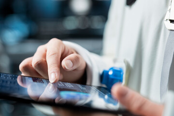 Close up of astronaut reviewing spacecraft metrics on tablet to ensure safe operation during long distance space travel. Orbital station crew member monitors system stability during cosmic journey