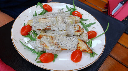 Chicken covered in white sauce and served with lettuce and tomatos