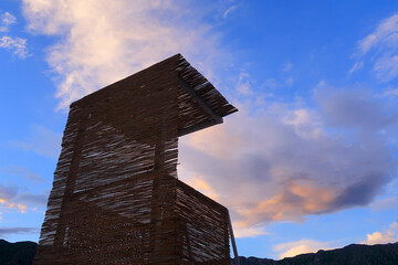 A wicker shelter set under a colourful blue evening sky
