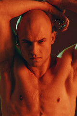 Intense man posing with a muscular physique, displaying confidence and focus in a dramatic light...