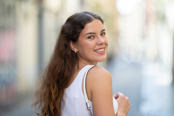 Long-haired cheerful female brunette walks along city street, spends time in motion, walks and...