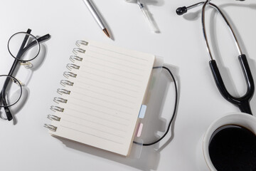 Top view of a doctor’s workspace showing a blank notepad, pen, and essential medical instruments for clinical planning and note-taking.