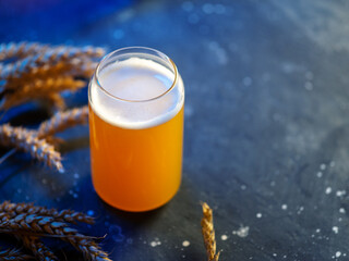 Craft draft beer on blue table with wheat ears and copy space