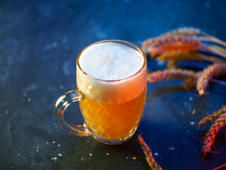 Beer foamy mug on dark blue table