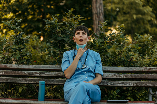 Healthcare worker taking break on park bench during pandemic