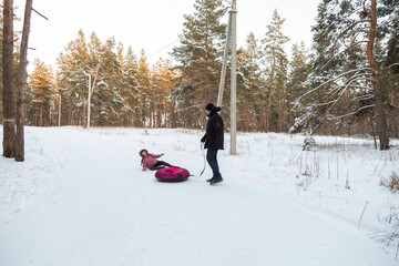 Father and daughter having fun with snow tube in the forest