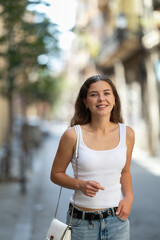 Carefree attractive young woman in mid twenties with fair skin and long hair walking outside on...