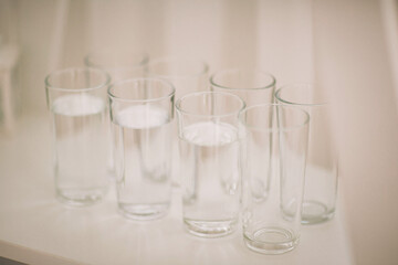 Refreshing glasses filled with crystal-clear water carefully arranged on a simple white table in a serene setting during a bright afternoon gathering