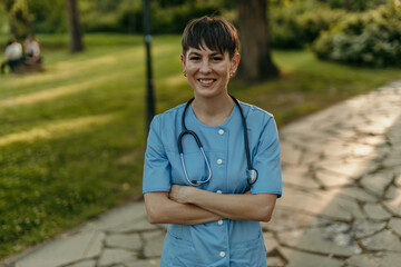 Smiling nurse in a park with arms crossed