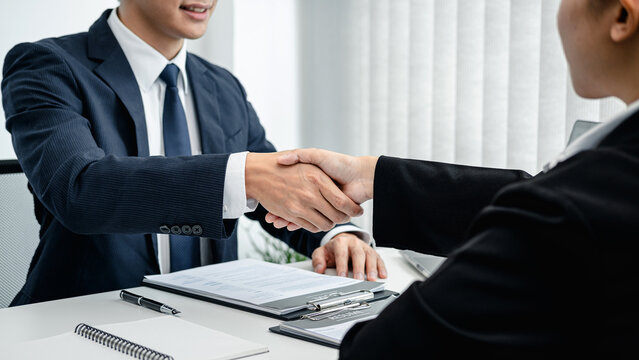 Man employer in suit shaking hands to congratulate with the new employee after successful with job interview