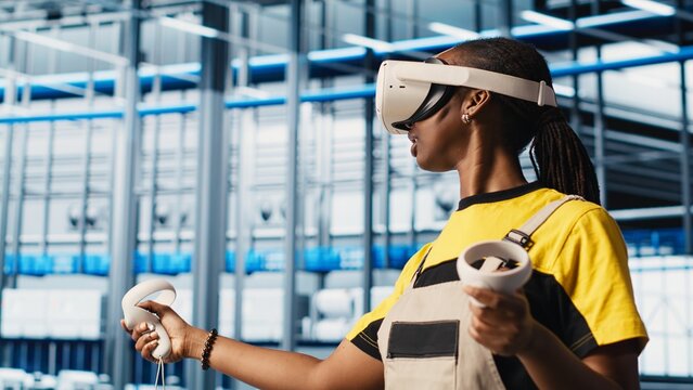 Engineer wearing VR headset in smart factory looking at collected data to do optimizations. Technicians using virtual reality in industry 4.0 industrial plant equipped with sensors, camera A