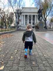Fototapeta premium little boy walking in town square