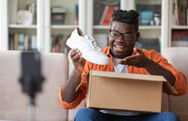 Social media influencer stylish cheerful chubby black guy reviewing product. Excited african...