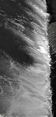 Vertical, black and white image. River mountain rapids. Dynamic composition. Abstract forms.