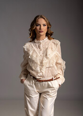 Fashion model posing in studio wearing white lace shirt and white pants