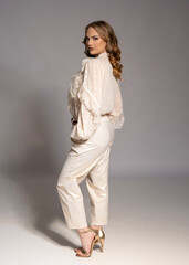 Fashion model posing in studio wearing white lace shirt and white pants