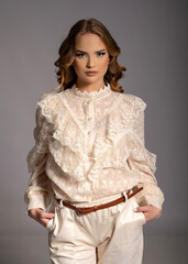 Fashion model posing in studio wearing white lace shirt and white pants