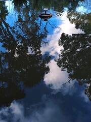 Reflections of trees and cloudy sky in the mirrored surface of the fountain. Colorful picture. A feeling of relaxation. Reflections of different shapes and shades. Abstract background