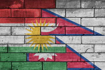 colourful painted big national flag of kurdistan and flag of nepal on a massive old brick wall background. concept