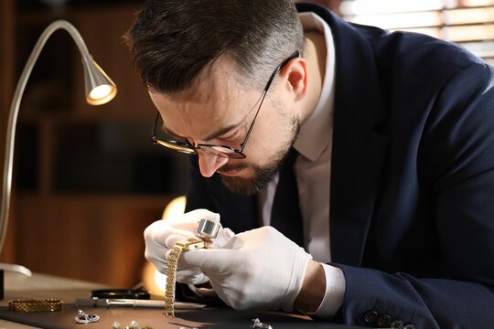 Appraiser with loupe evaluating luxury wristwatch at table indoors