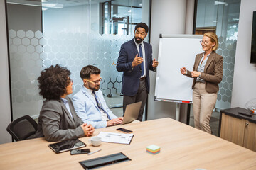 Man and woman tutors present project on whiteboard to diverse colleagues