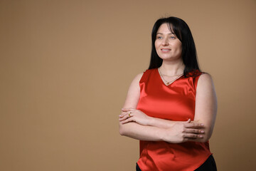 Obraz premium Portrait of smiling plus size model on beige background, space for text. Overweight