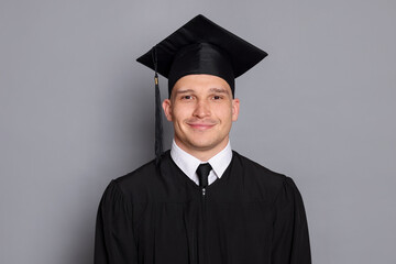 Portrait of student after graduation on grey background