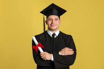 Student with diploma after graduation on yellow background