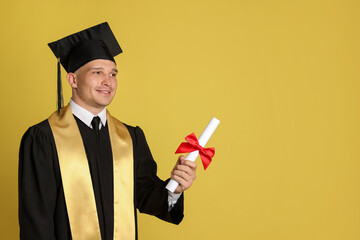 Happy student with diploma after graduation on yellow background. Space for text