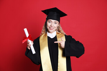 Happy student pointing at diploma after graduation on red background