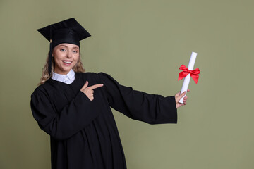 Happy student pointing at diploma after graduation on green background