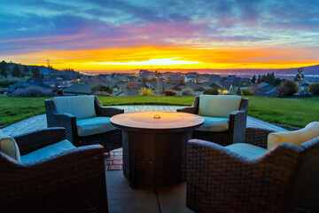 A colorful sunset above the city lights of Spokane, Washington, seen from a patio terrace with chairs and a fire pit in the suburban community of Liberty Lake, Washington.
