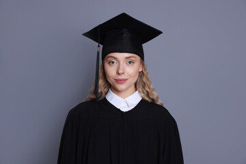 Student in mortarboard after graduation on grey background