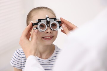Ophthalmologist examining girl's vision with trial frame in clinic, closeup