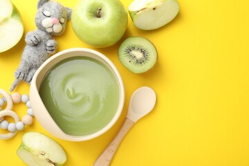 Baby food. Tasty puree in bowls, different ingredients and toys on yellow background, flat lay. Space for text