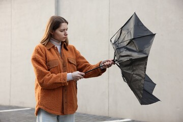 Teenage girl with black broken umbrella outdoors