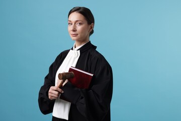 Judge with mallet and book on light blue background