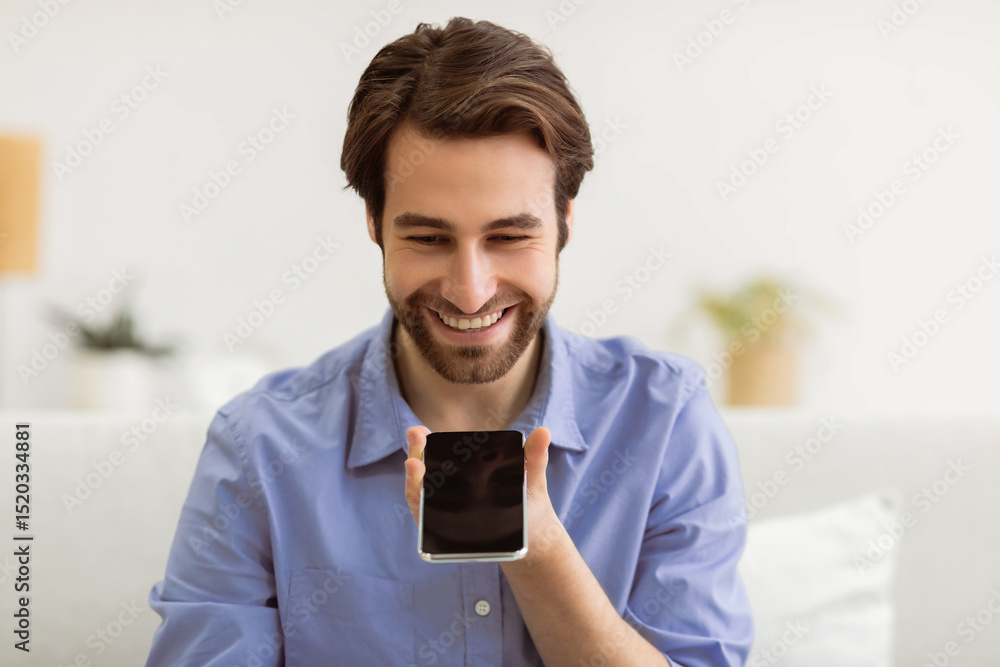 Poster voice assistant app. cheerful man using smartphone with voice search application sitting on couch at