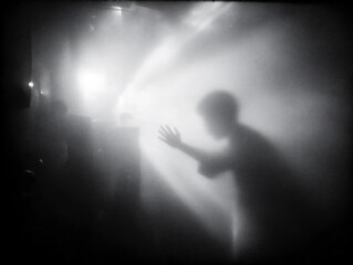 blurry photograph of a hand reaching out from a dark, unseen space