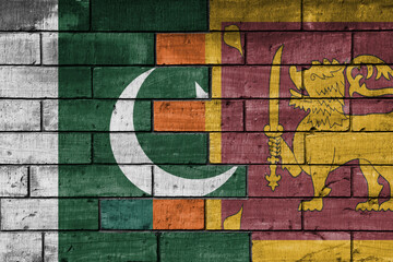 Fototapeta premium colourful painted big national flag of sri lanka and flag of pakistan on a massive old brick wall background. concept
